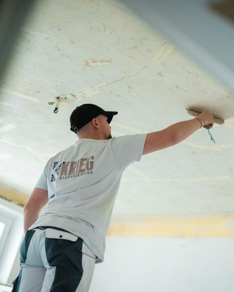 Facharbeiter von Krieg Bausanierung bei der professionellen Deckenspachtelung während einer Innenraumsanierung.