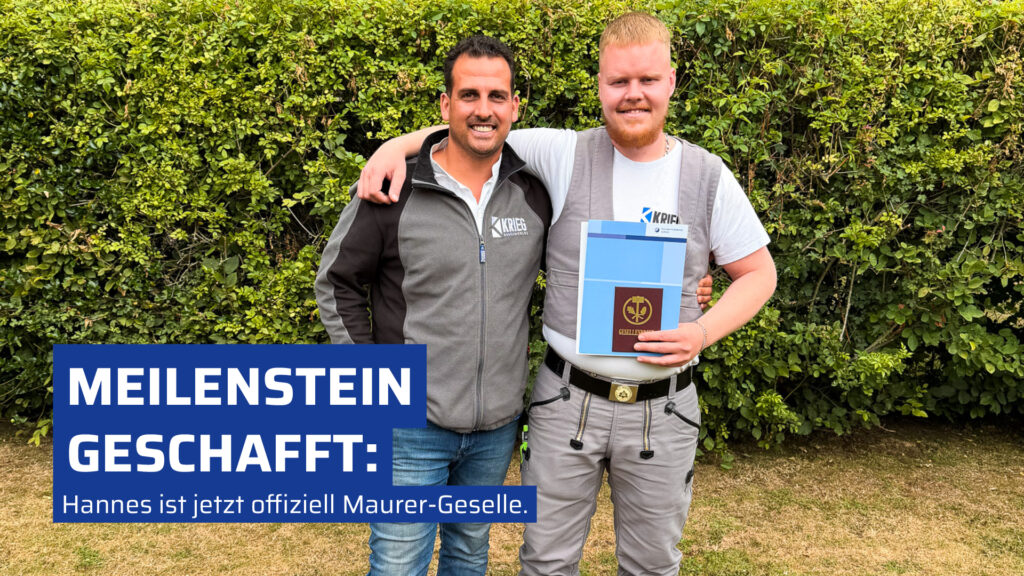 Bauleiter Sebastian Berdel gratuliert Maurer-Geselle Hannes Schwalba zur bestandenen Gesellenfreisprechung bei der Krieg Bauunternehmung. Die beiden Männer stehen lächelnd vor einer Hecke, Hannes hält seinen Gesellenbrief im traditionellen Maurer-Outfit in der Hand.