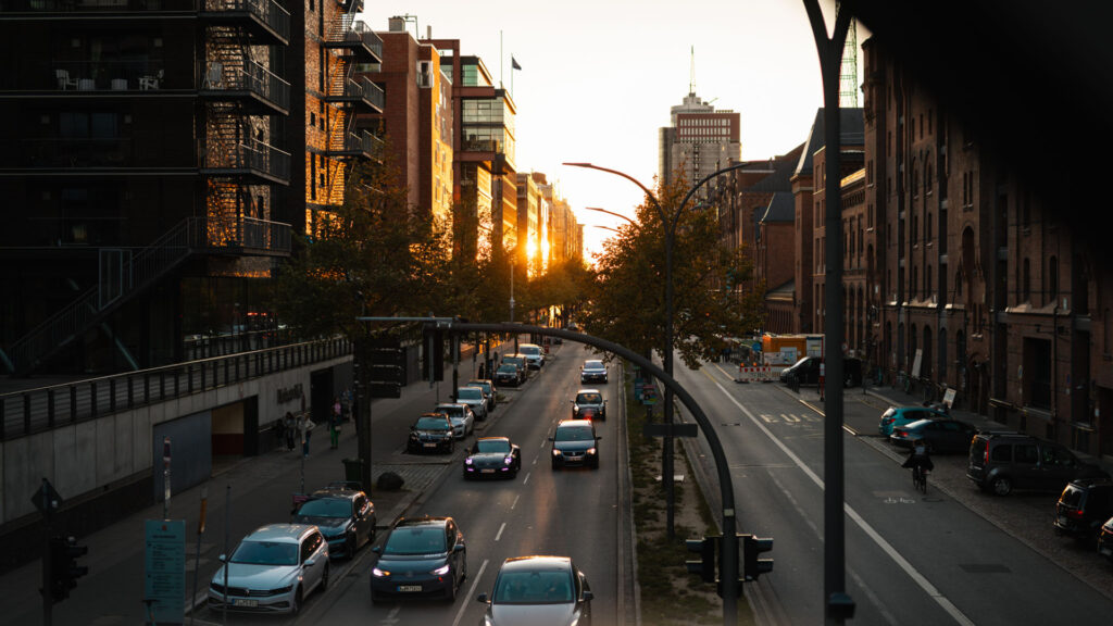 Blick auf den Straßenverkehr in der Hamburger Speicherstadt während des Sonnenuntergangs mit modernen Gebäuden und Backsteinarchitektur