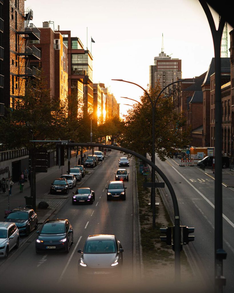 Blick auf den Straßenverkehr in der Hamburger Speicherstadt während des Sonnenuntergangs mit modernen Gebäuden und Backsteinarchitektur