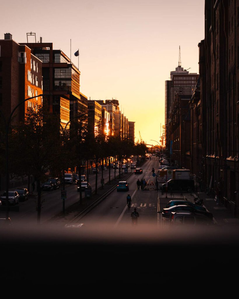 Städtische Straßenszene in der Hamburger Speicherstadt bei Abenddämmerung mit Blick auf das Mundsburg-Hochhaus im Hintergrund