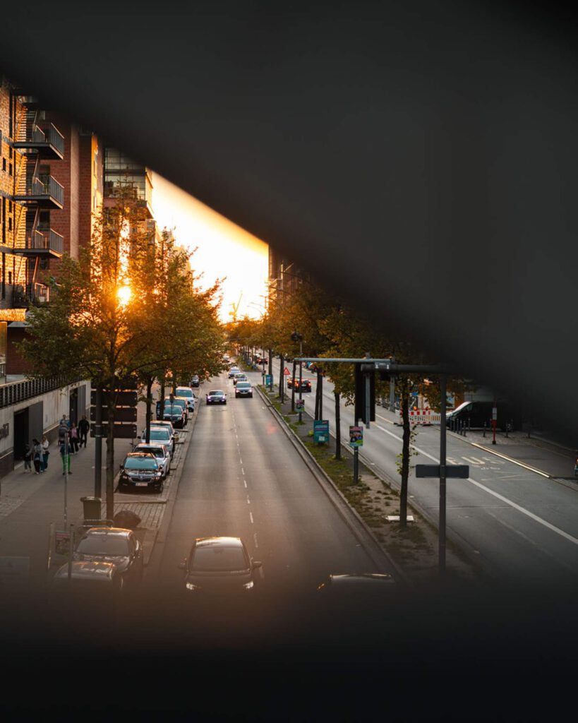 Kreative Rahmung einer Straße in der Hamburger Speicherstadt mit tiefstehender Sonne und Stadtverkehr